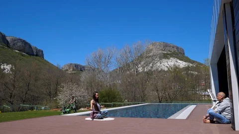 Open air stretch. Yoga. By the pool. Girl with a trainer doing a yoga exercises Stock Footage 129555421