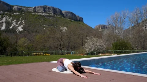 Open air stretch. Yoga. By the pool. The girl with long dark hair doing yoga. Stock Footage 129555435
