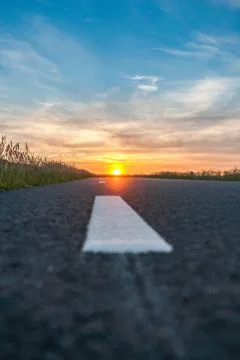 Open asphalt road towards the setting sun Stock Photos