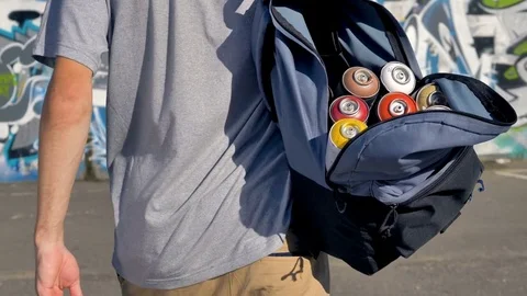 An open backpack full of paint cans on graffiti artist shoulder. Stock Footage