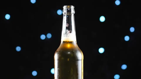 Open beer bottle close-up. Light beer in bottle rotated over black background. Stock Footage 112676061