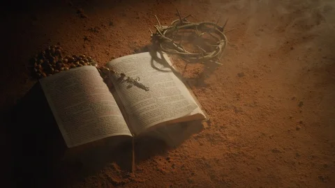 Open Bible with crown of thorns and cross on dusty surface.  Shot with RED 8K Stock Footage 130357353