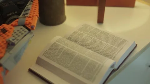Open bible next to lamp, camera and lego on shelf Stock Footage 157081096