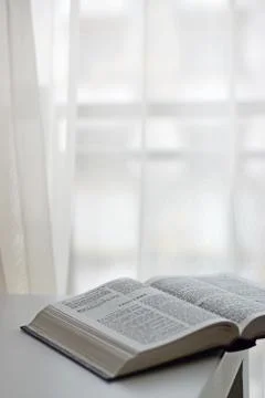 Open bible next to the window Stock Photos