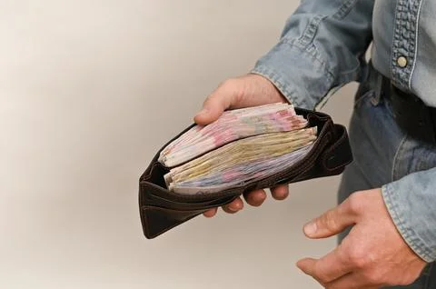 Open billfold reveals substantial amount of held cash money. Stock Photos