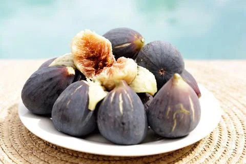 Open black fig with red core on a full of figs dish Stock Photos