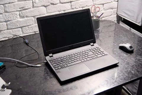 Open black laptop with blank screen on black marble desk near computer mous.. Stock Photos