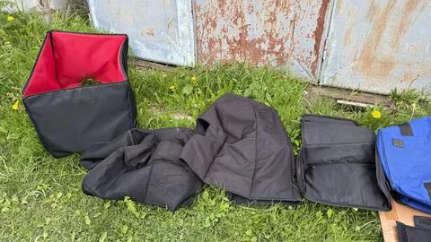 Open black square equipment bag with bright red lining and other folded soft Stock Photos