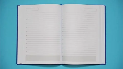 An open blank diary closes and rolls away on blue background. Stop motion Stock Footage 290179243