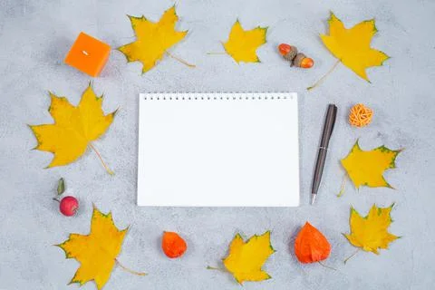 An open blank diary notebook, calendar and yellow leaves on grey concrete table Stock Photos