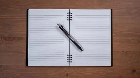 Open blank lined notebook with a pen laying on top with a wooden background Stock Photos