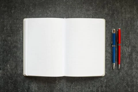 Open blank notebook and 2 colored metallic pens on dark gray background Stock Photos
