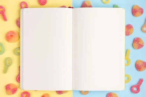 Open blank notebook on background of gummy candies. Multicolored candies on y Stock Photos