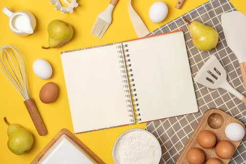Open blank notebook, baking ingredients and cooking utensil, on yellow backgr Stock Photos