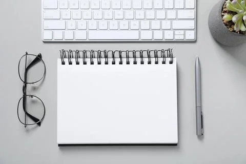 Open blank notebook, computer keyboard, glasses, pen and floral decor on li.. Stock Photos