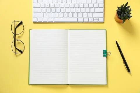 Open blank notebook, computer keyboard, glasses, pen and floral decor on ye.. Stock Photos