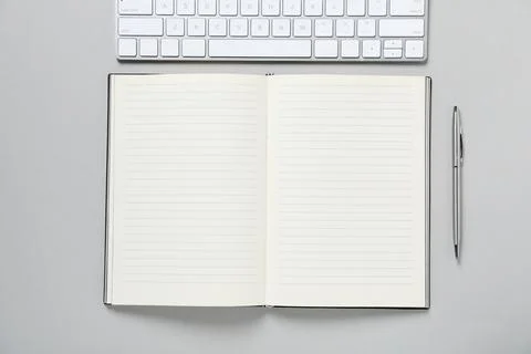 Open blank notebook, computer keyboard and pen on light grey background, fl.. Foto stock