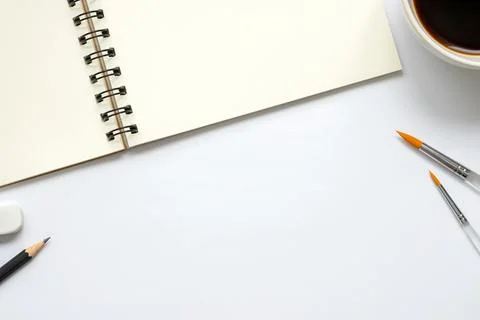 Open Blank Notebook with a Cup of Coffee, Paintbrush, Pencil and Eraser Foto stock