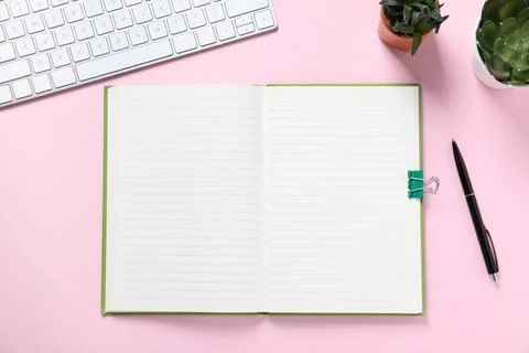 Open blank notebook, pen, computer keyboard and floral decor on pink backgr.. Foto stock