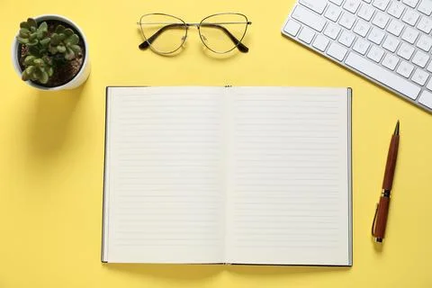 Open blank notebook, pen, glasses, computer keyboard and floral decor on ye.. Stock Photos