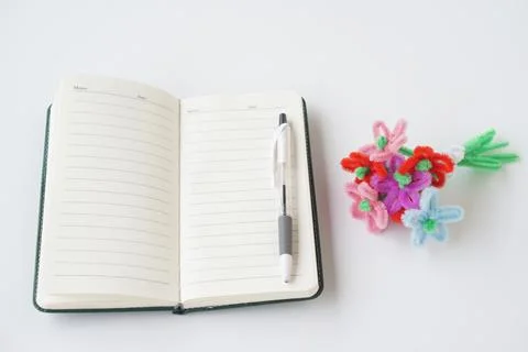 Open blank notebook with pen placed on white background next to colorful handmad Stock Photos