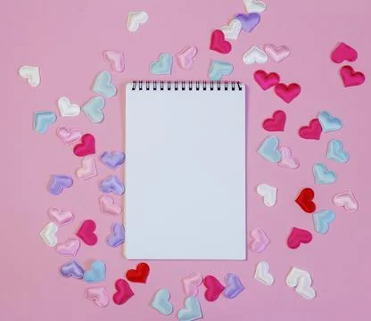 An open blank notebook on a pink background with hearts. Stock Photos