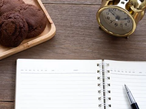 The open blank notebook side of the cookie and there is a golden clock in the Stock Photos