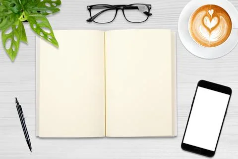 An open blank notebook, smartphone with pen and a cup of latte coffee on wo.. Stock Photos