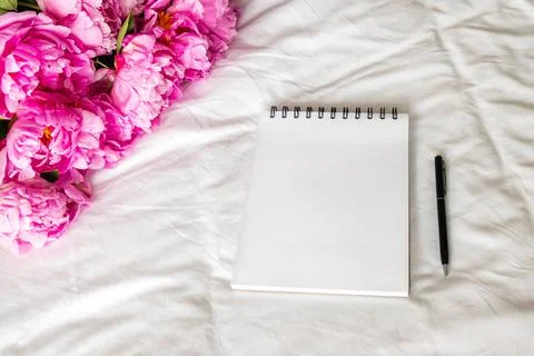 Open blank notepad and pink peonies. Stock Photos