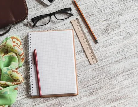 Open a blank Notepad, pen, glasses, phone, handbag and scarf on white woode.. Fotos de archivo