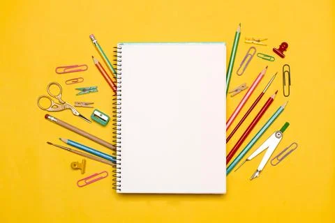 An open blank notepad with scissors, colored pencils, paper clips and a compass Foto stock