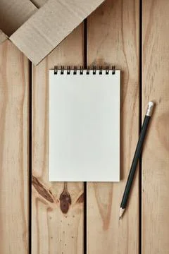 Open Blank Spiral Notebook with Open Empty Cardboard Box on Wood Table Foto stock