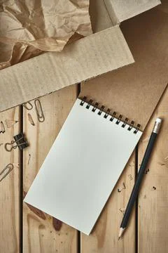 Open Blank Spiral Notebook with Open Empty Cardboard Box and Black Pencil Foto stock