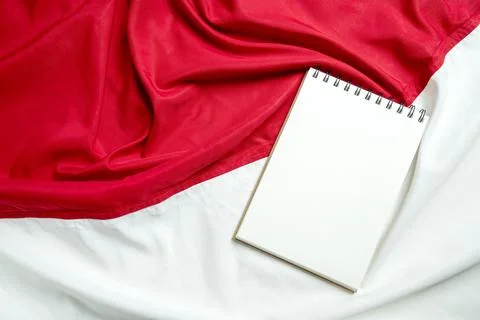 An open blank spiral notebook with white paper placed on a textured red and.. Stock Photos