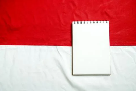 An open blank spiral notebook with white paper placed on a textured red and.. Stock Photos