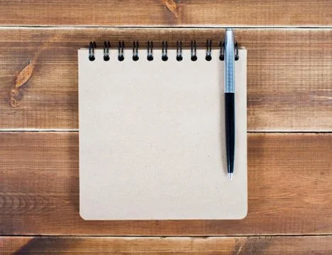 An open blank square notebook of brown kraft paper with a spiral and a ballpo Stock Photos