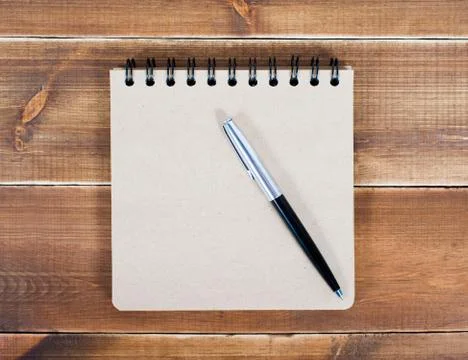 An open blank square notebook of brown kraft paper with a spiral and a ballpo Stock Photos