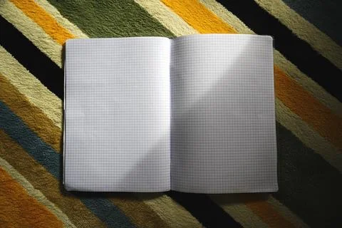 Open blank squared notebook placed on a colorful striped carpet with soft n.. Stock Photos