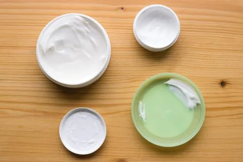 Open body and face creams on a natural wood background Stock Photos