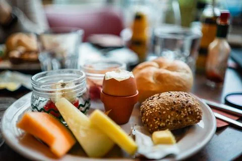 Open Boiled Egg in the Middle of a Breakfast Plate with Bread and Fruits Stock Photos