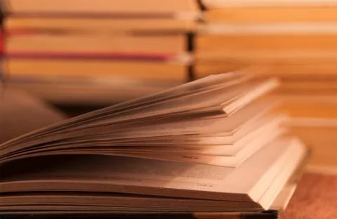 Open book against the background of a stack of other books Stock Photos
