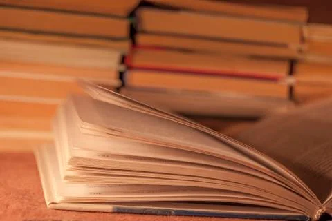 Open book against the background of a stack of other books, in warm tinting Foto stock