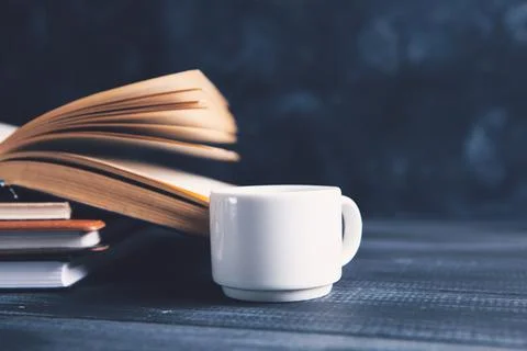 An open book and a cup on the table Stock Photos