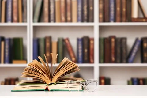 Open book and eyeglasses on table in stylish home library, closeup Fotos de archivo