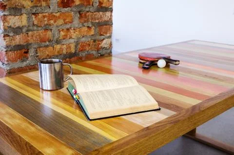 Open book and a racket ping pong, lying on a wooden table Stock Photos