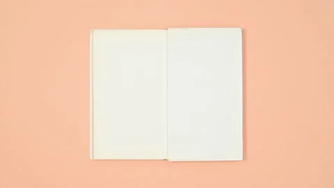 An open book with blank pages on a solid pastel orange background, top view Stock Footage 346239859