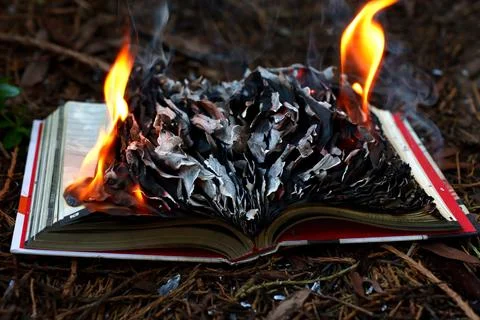 Open Book Burning with Bright Flames and Ash Against a Black Background Stock Photos