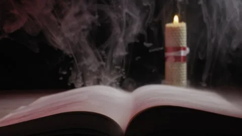 Open Book with Burning Candle and Mystical Smoke in the Dark Stock Footage 329606037