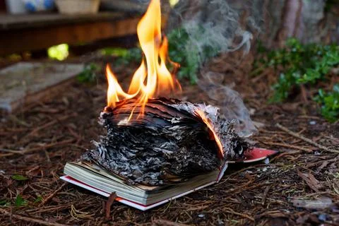 Open Book Burning on the Ground Symbolizing Censorship and Lost Knowledge Photos