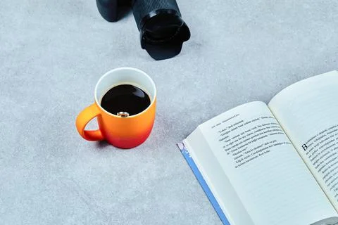 Open book, camera and coffee cup on gray table Stock Photos